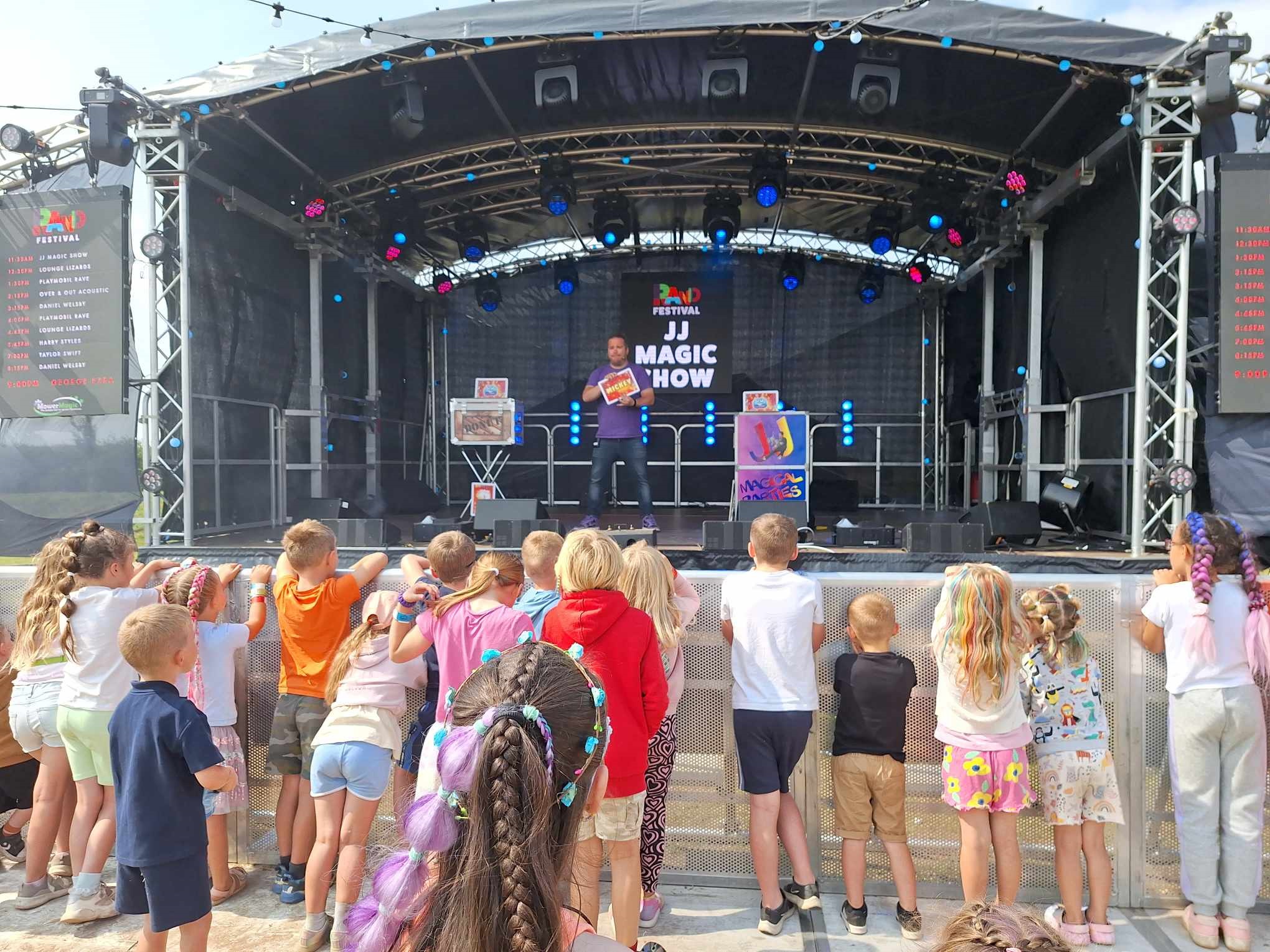 JJ performing magic on stage at a family festival